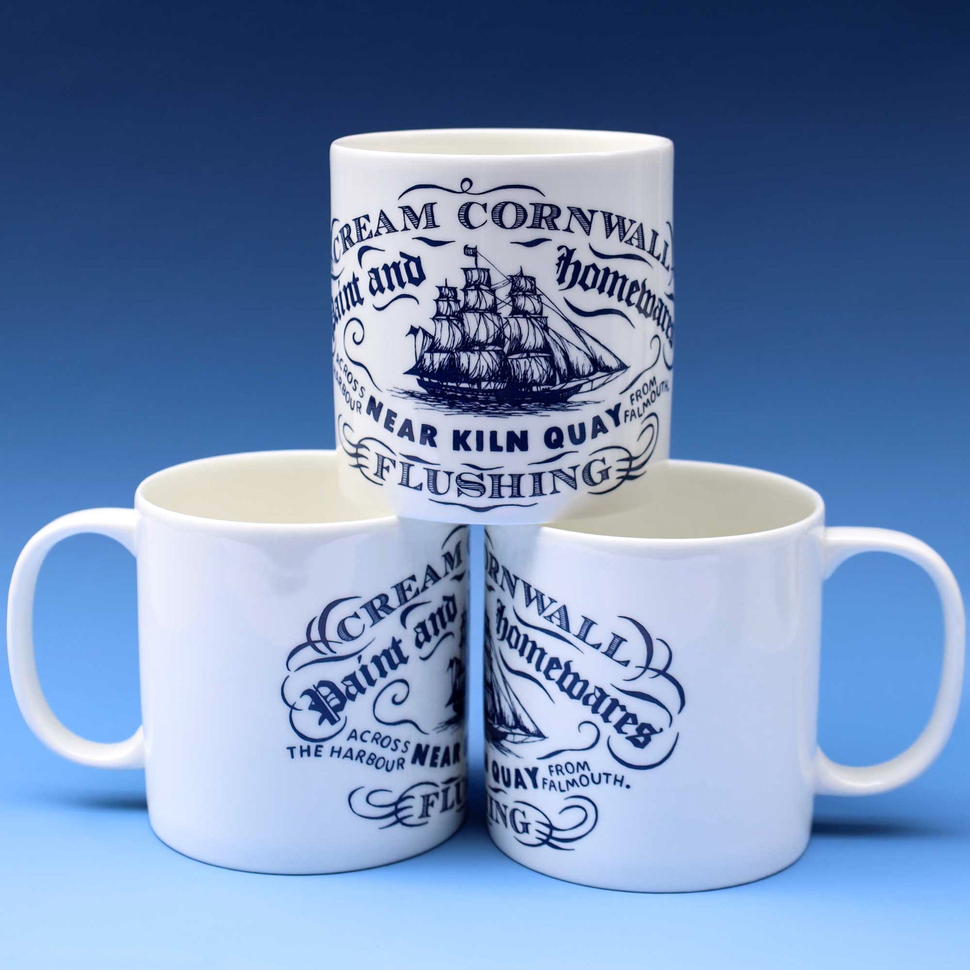 Three white ceramic mugs with blue printed text and a ship illustration, arranged in a pyramid on a blue gradient background.