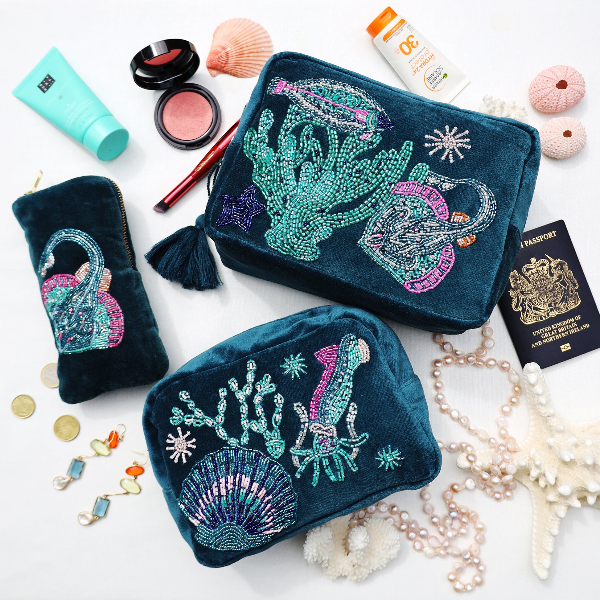 Two blue makeup bags with sea-themed designs on a white surface with accessories.