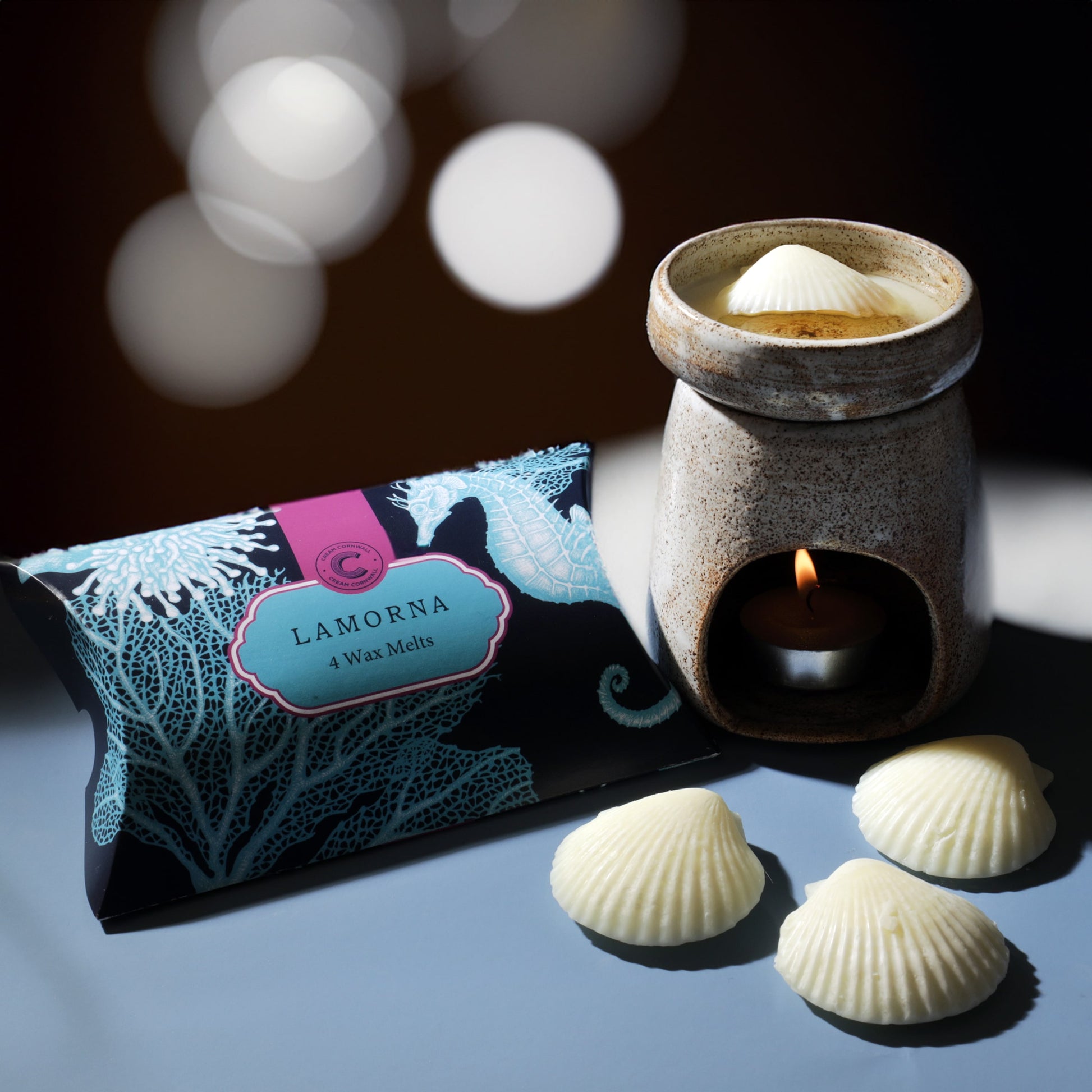 Lamorna wax melts packaging with a ceramic warmer and melts on a reflective surface.