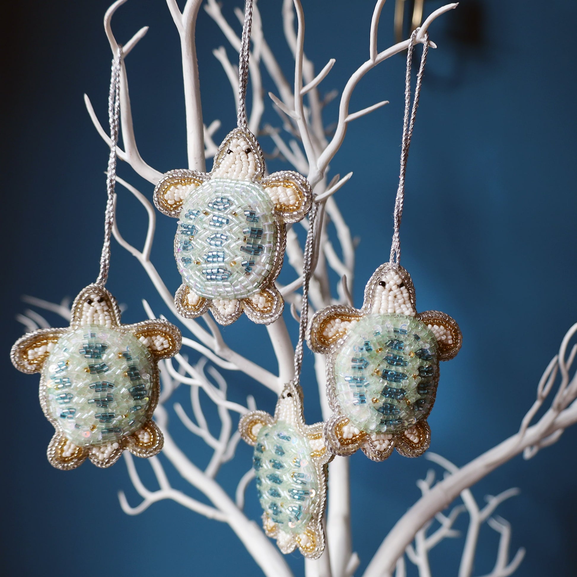 Decorative turtle ornaments hanging on a branch against a blue background