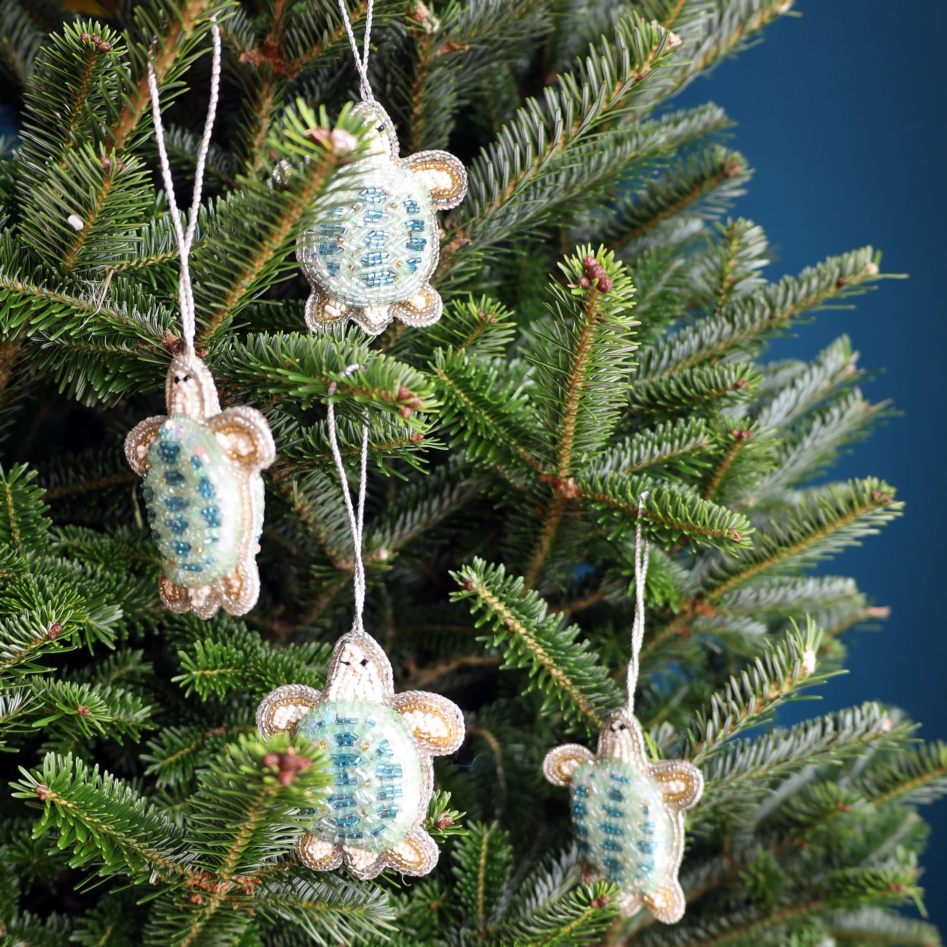 Decorative turtle ornaments hanging on a Christmas tree.
