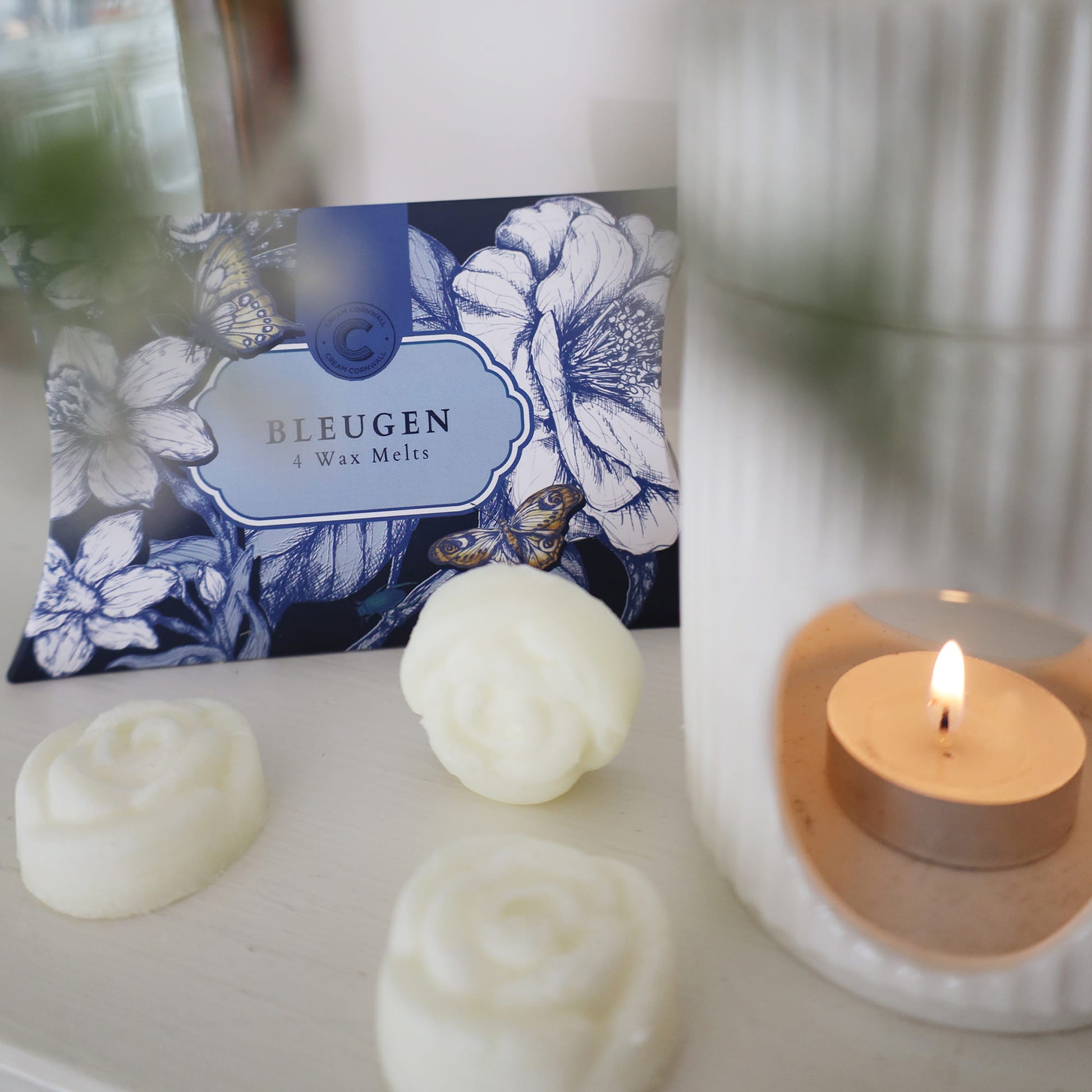 Bleugen wax melts with a lit candle on a white surface