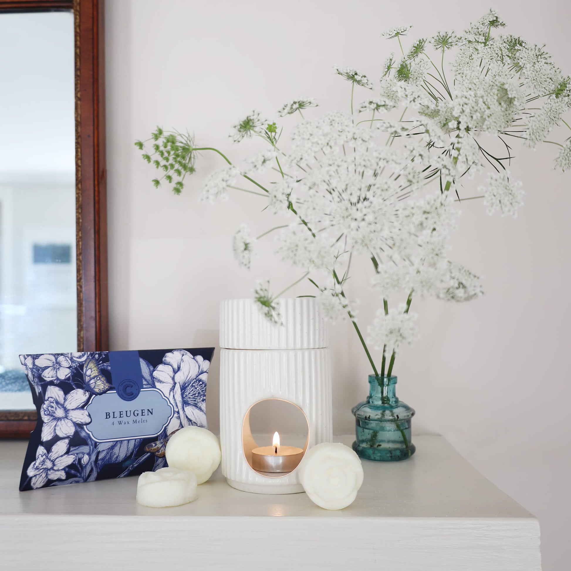 Decorative items including a candle, vase with flowers, and decorative pillow on a white surface.