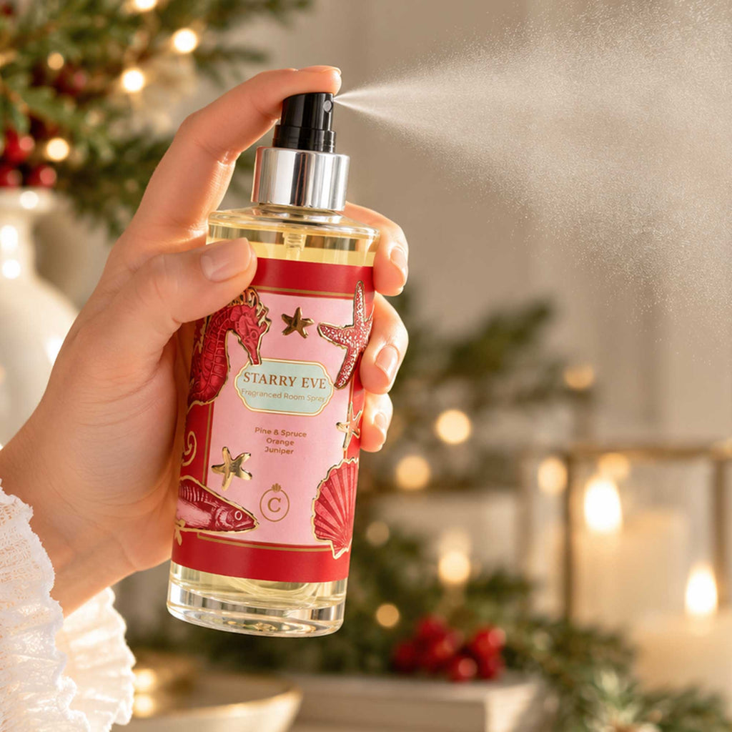 Cream Cornwall Starry Eve room spray being misted over a festive Christmas table, surrounded by candlelight, greenery and rich red seasonal details.