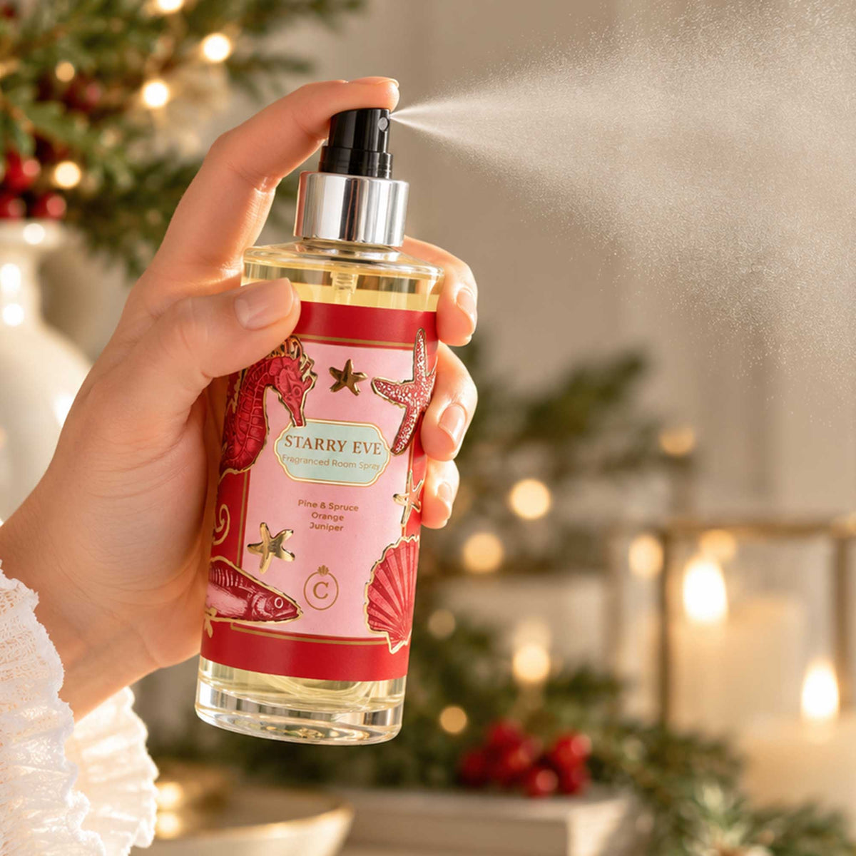 Cream Cornwall Starry Eve room spray being misted over a festive Christmas table, surrounded by candlelight, greenery and rich red seasonal details.