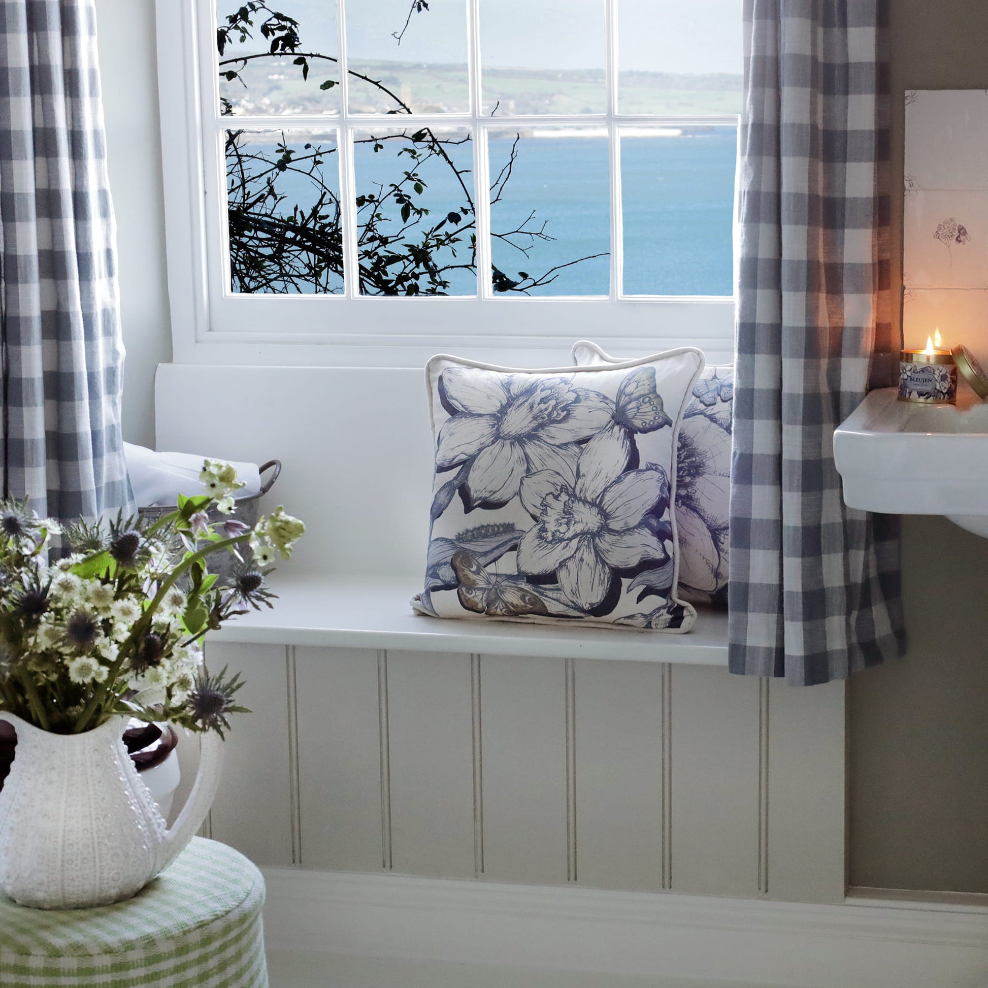 Nautical-themed room with a window, bench, and decorative daffodil pillows.