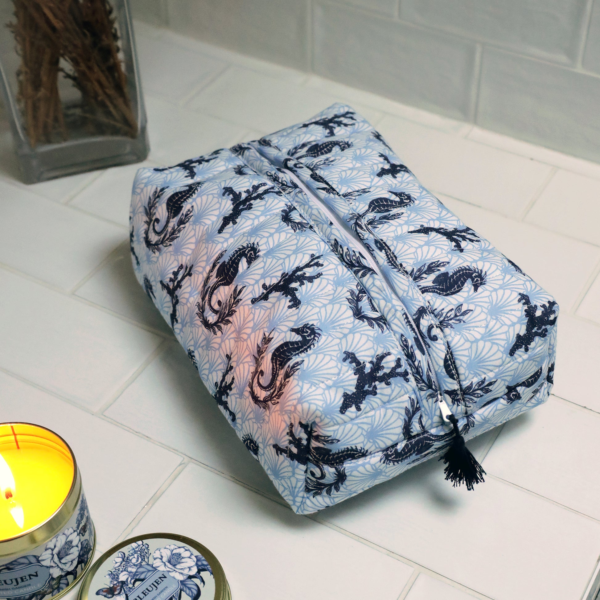 Blue pouch with black dragon pattern on a tiled surface next to a lit candle.