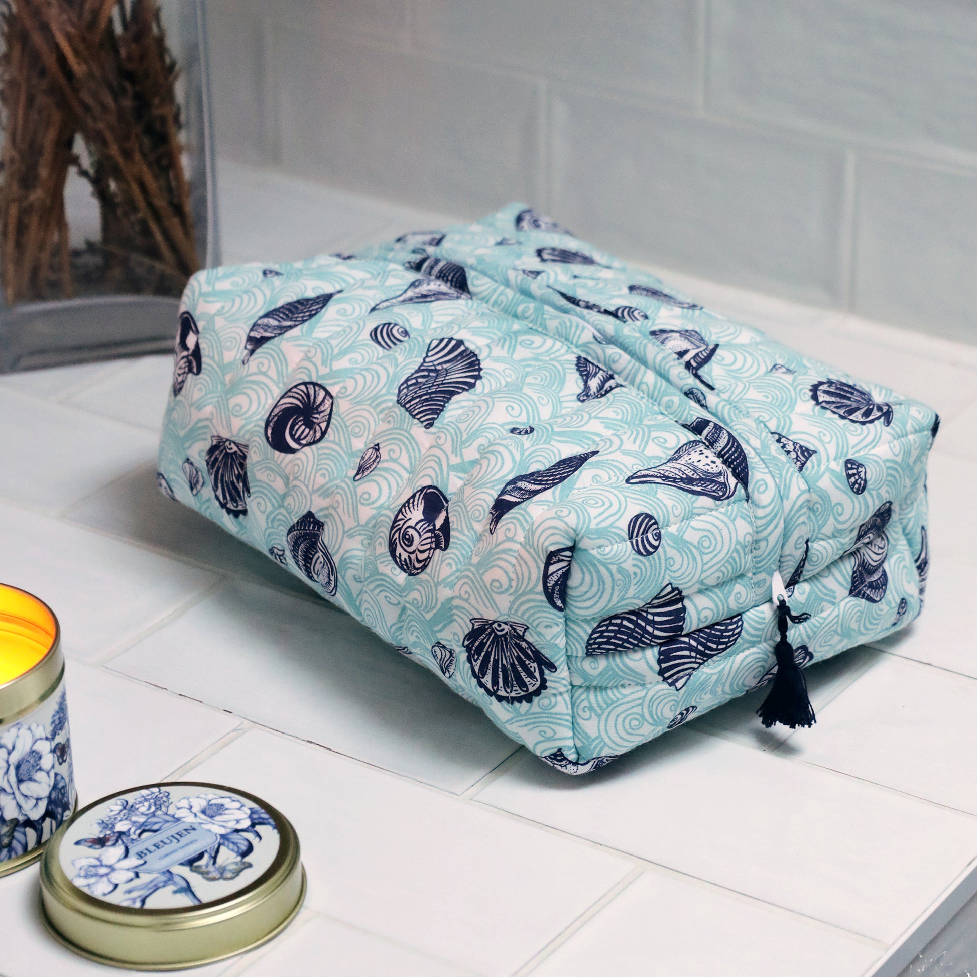 Blue and white patterned toiletry bag on a tiled surface with two containers.