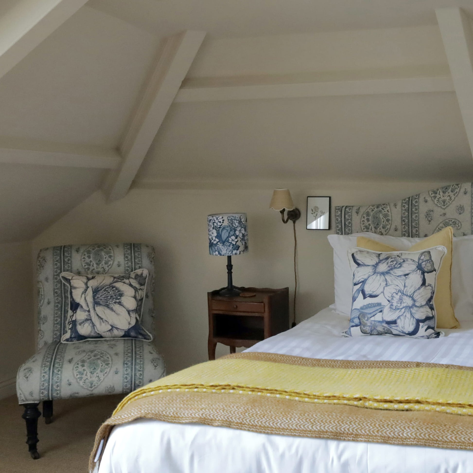 Bedroom with floral-patterned chair, bed, and lamp.