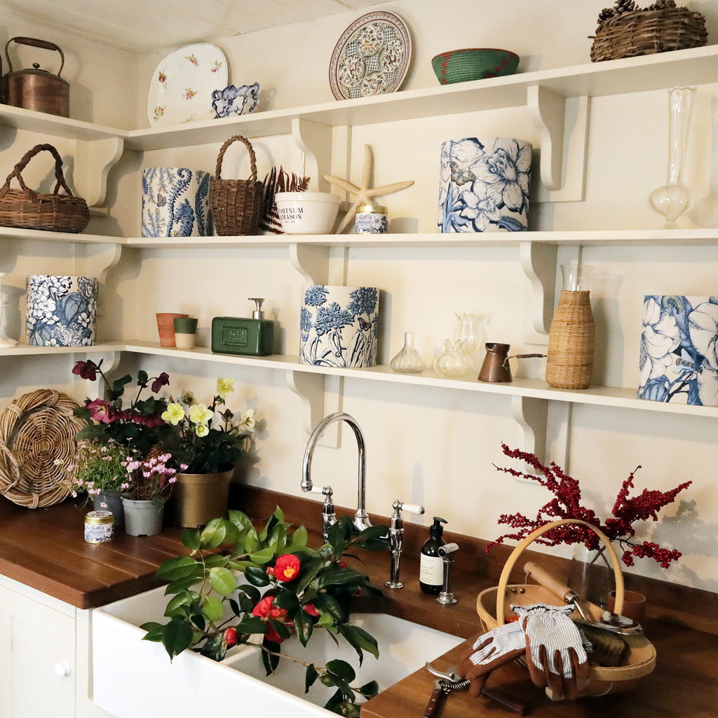 Shelves with decorative items above a kitchen sink and floral lampshades.