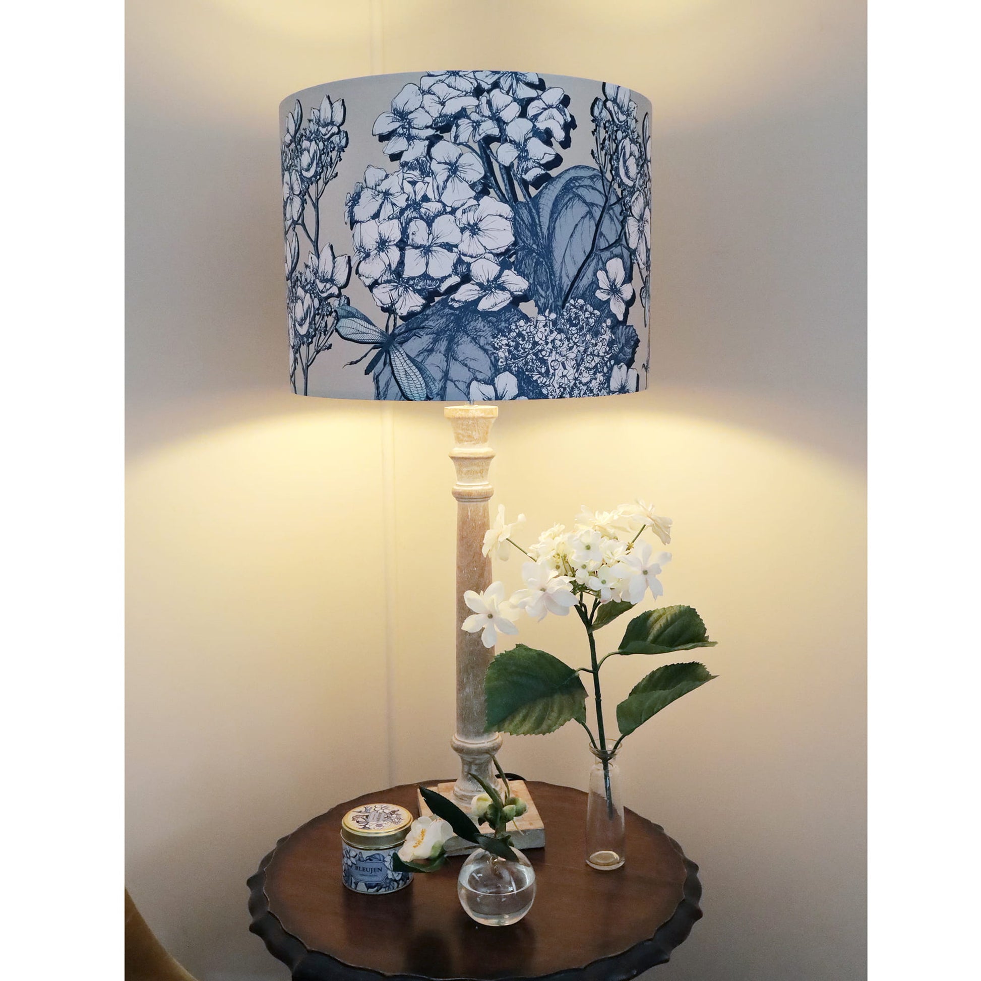 Table lamp with hydrangea patterned shade on a wooden table with decorative items.