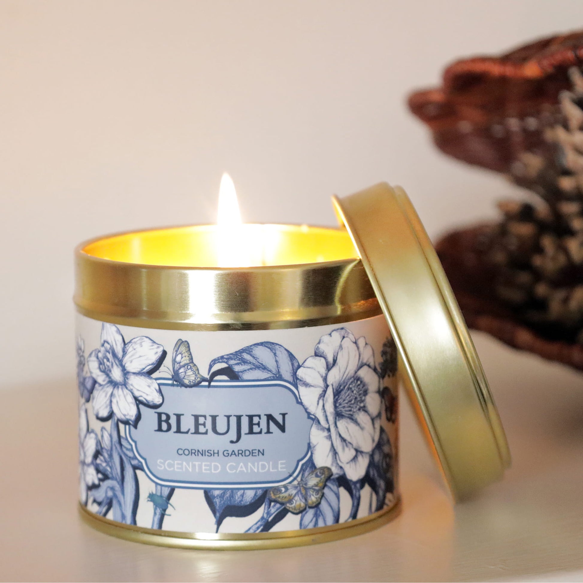 Candle in a decorative tin with floral design and 'BLEUJEN' branding.
