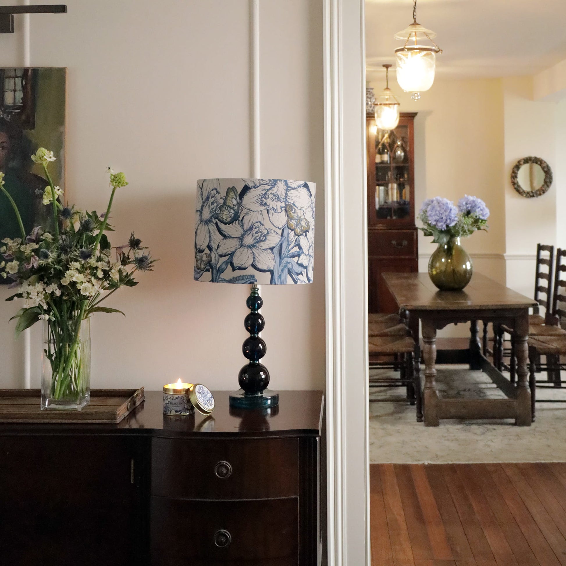 Living room with a lamp, flowers, and a candle on a table.