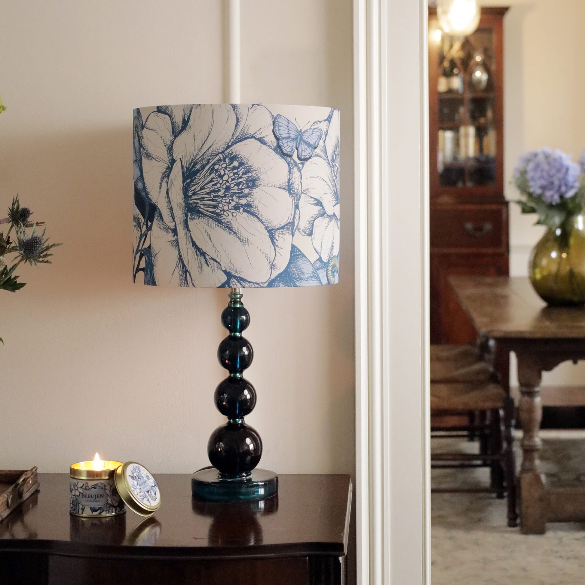 Decorative camelia lamphade with on a table in a room setting.