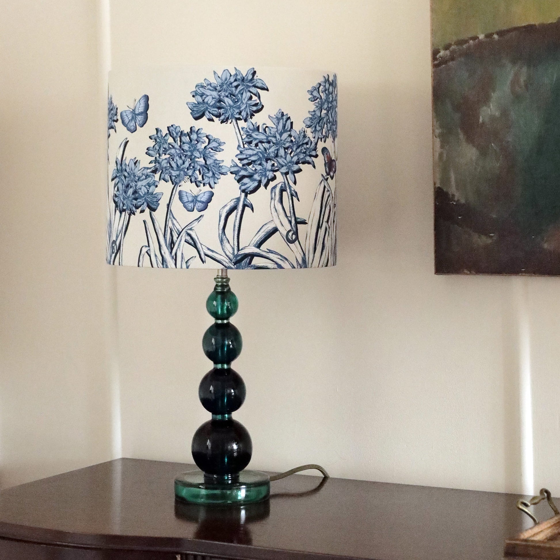 Table lamp with a agapanthus patterned shade on a wooden surface.