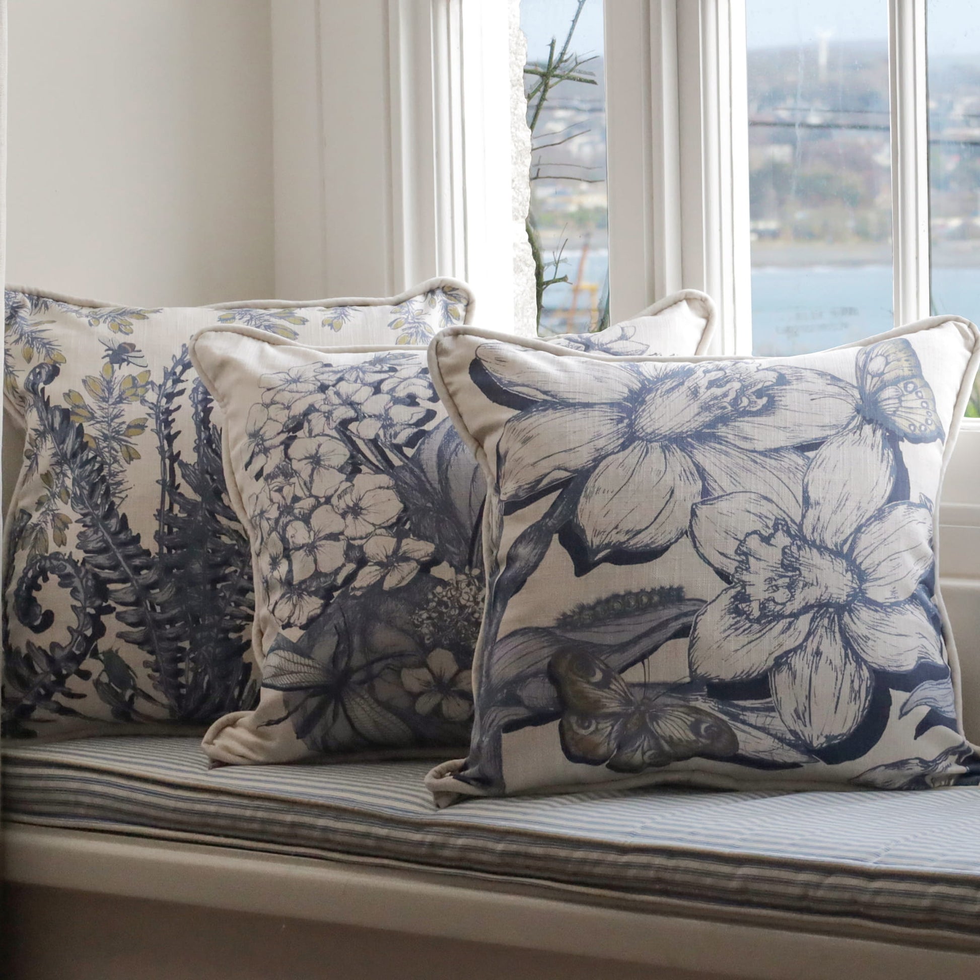 Cornish floral  patterned cushions on a window seat with a scenic view outside.