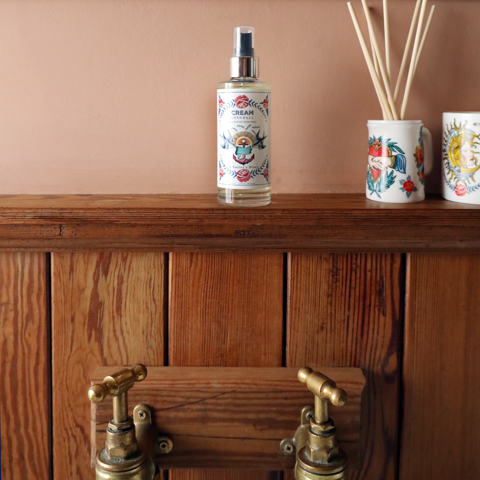 Fragrance Room Spray glass bottle with atomiser top,on a wooden shelf in a bathroom,next to a Sailor Story candle and diffuser.
