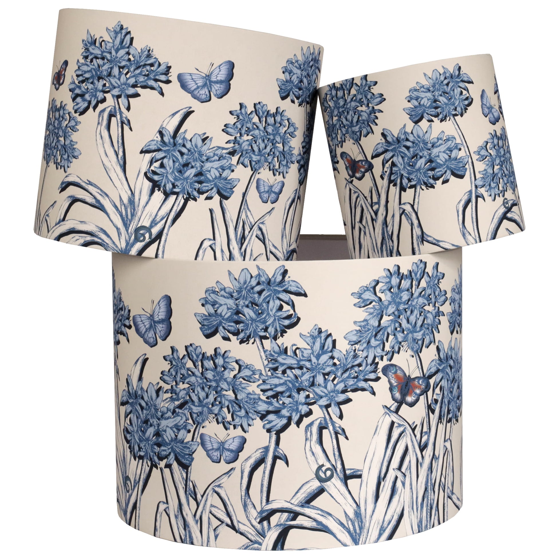 Set of three cylindrical lampshades with blue agapanthus and butterfly design on a beige background
