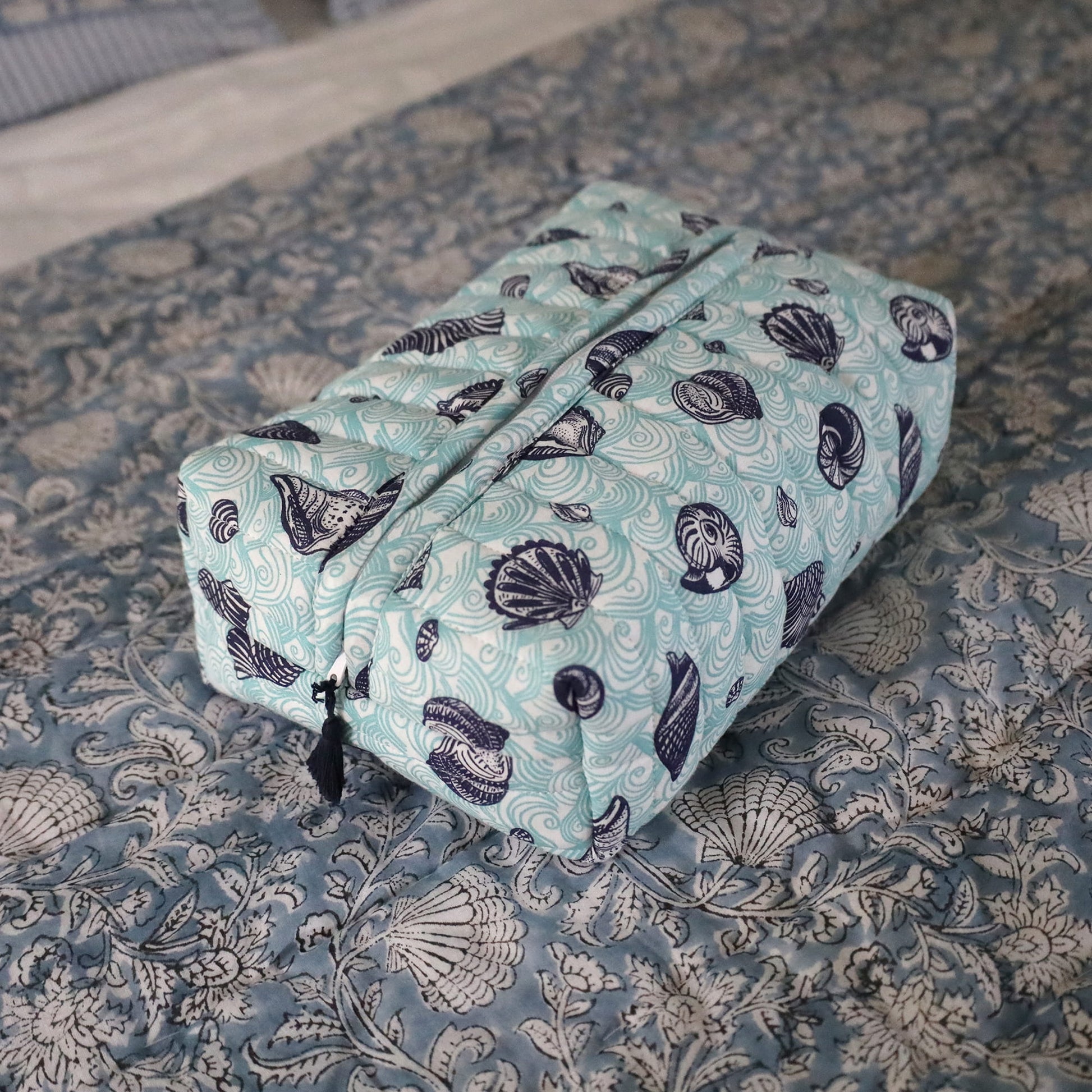 Aqua & navy shell and sea patterned wash bag on block printed  quilt.