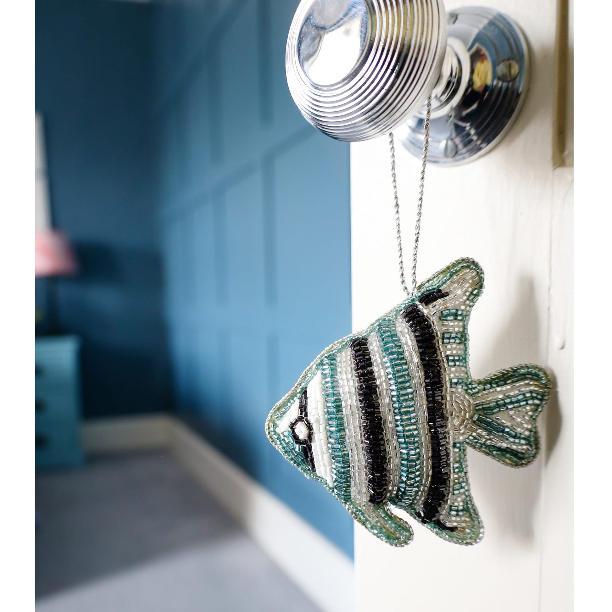 Decorative fish ornament hanging on a light switch with a blurred background
