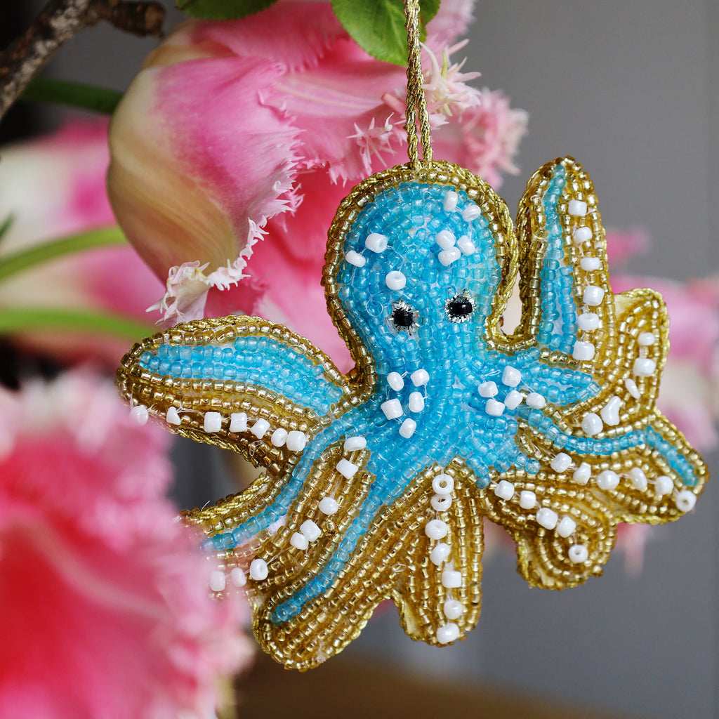Decorative octopus ornament with blue and gold details against a blurred floral background
