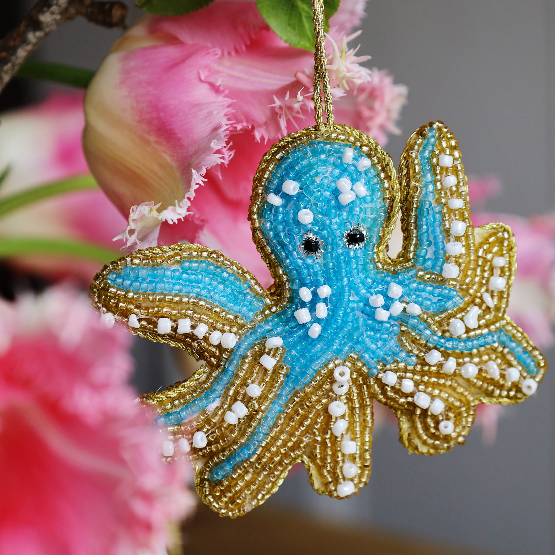 Decorative octopus ornament with blue and gold details against a blurred floral background