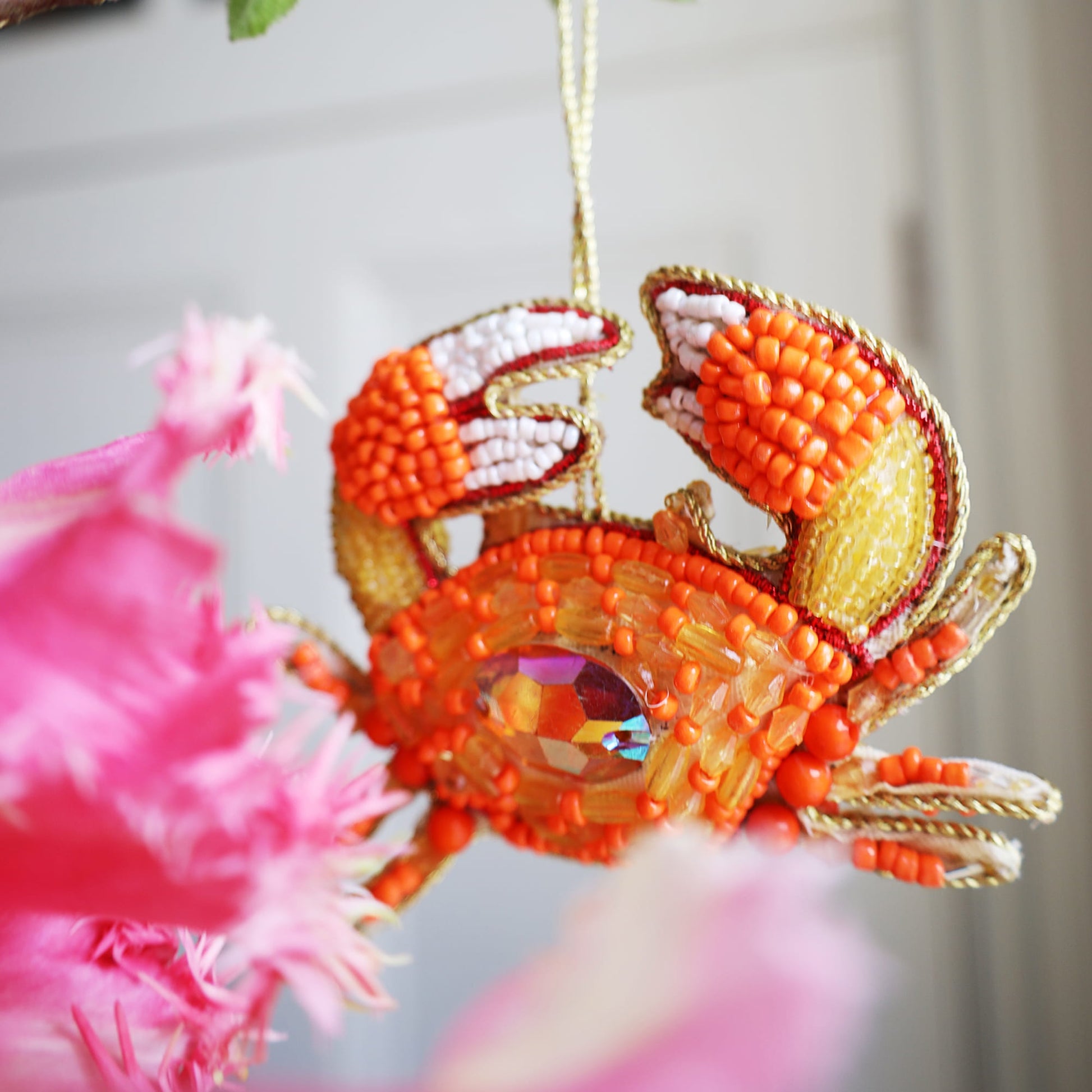 Decorative crab ornament with beads and feathers on a blurred background