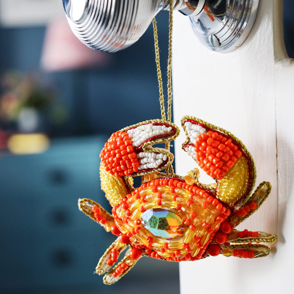 Decorative beaded crab ornament hanging from a light fixture.