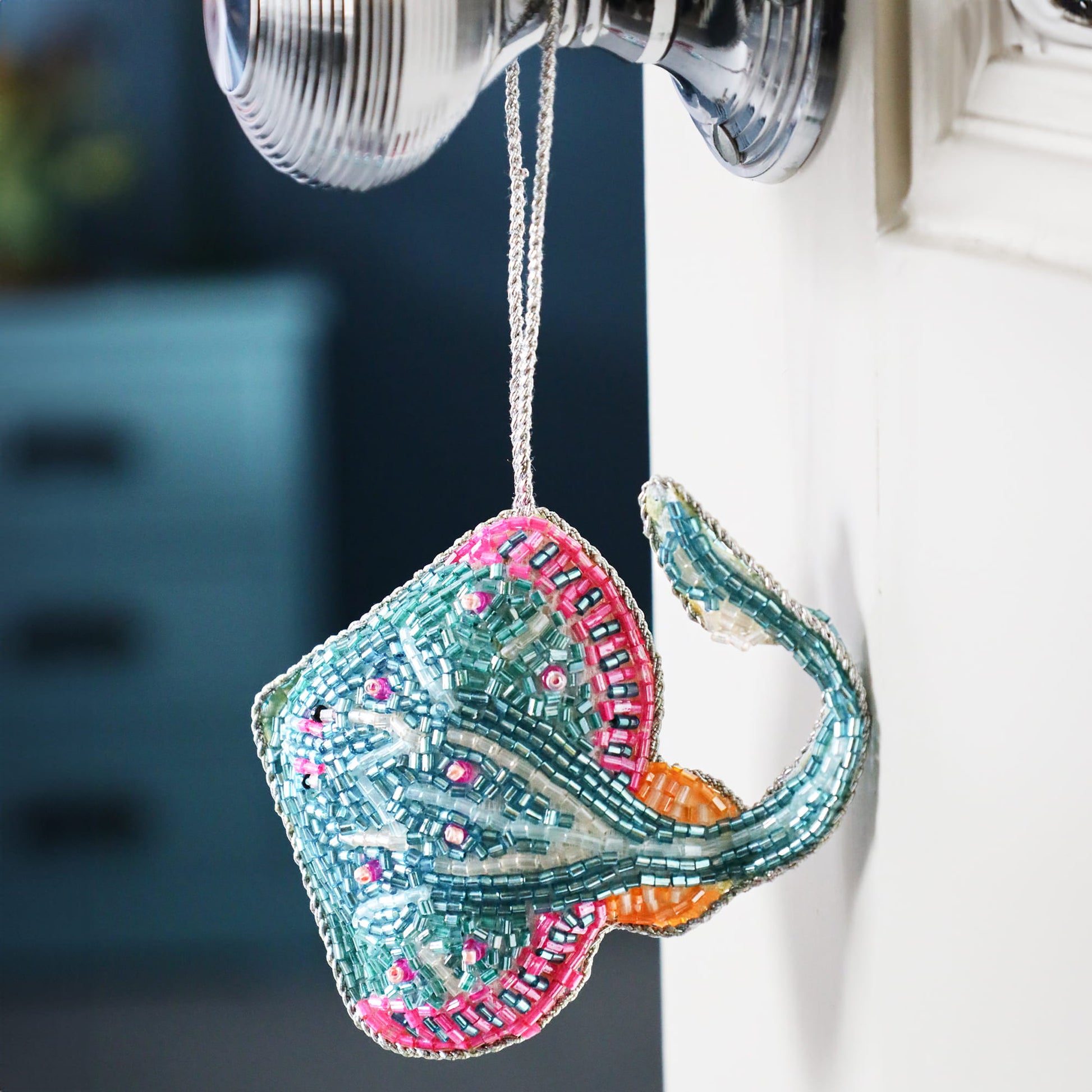 Decorative stingray ornament with beaded details hanging on a hook.