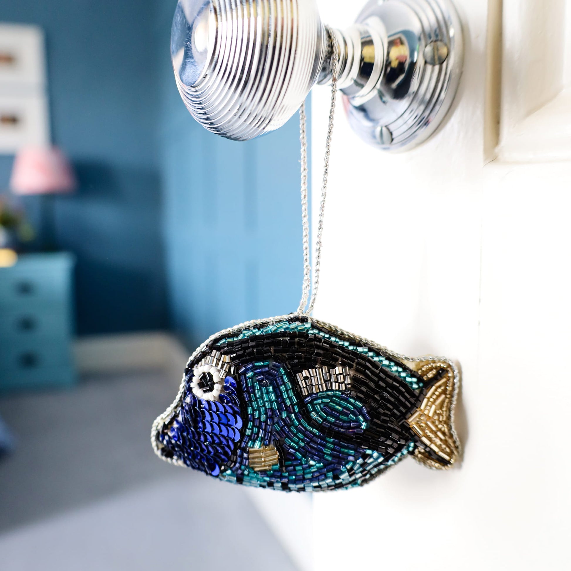 Decorative fish ornament hanging on a wall light fixture with a blurred room background