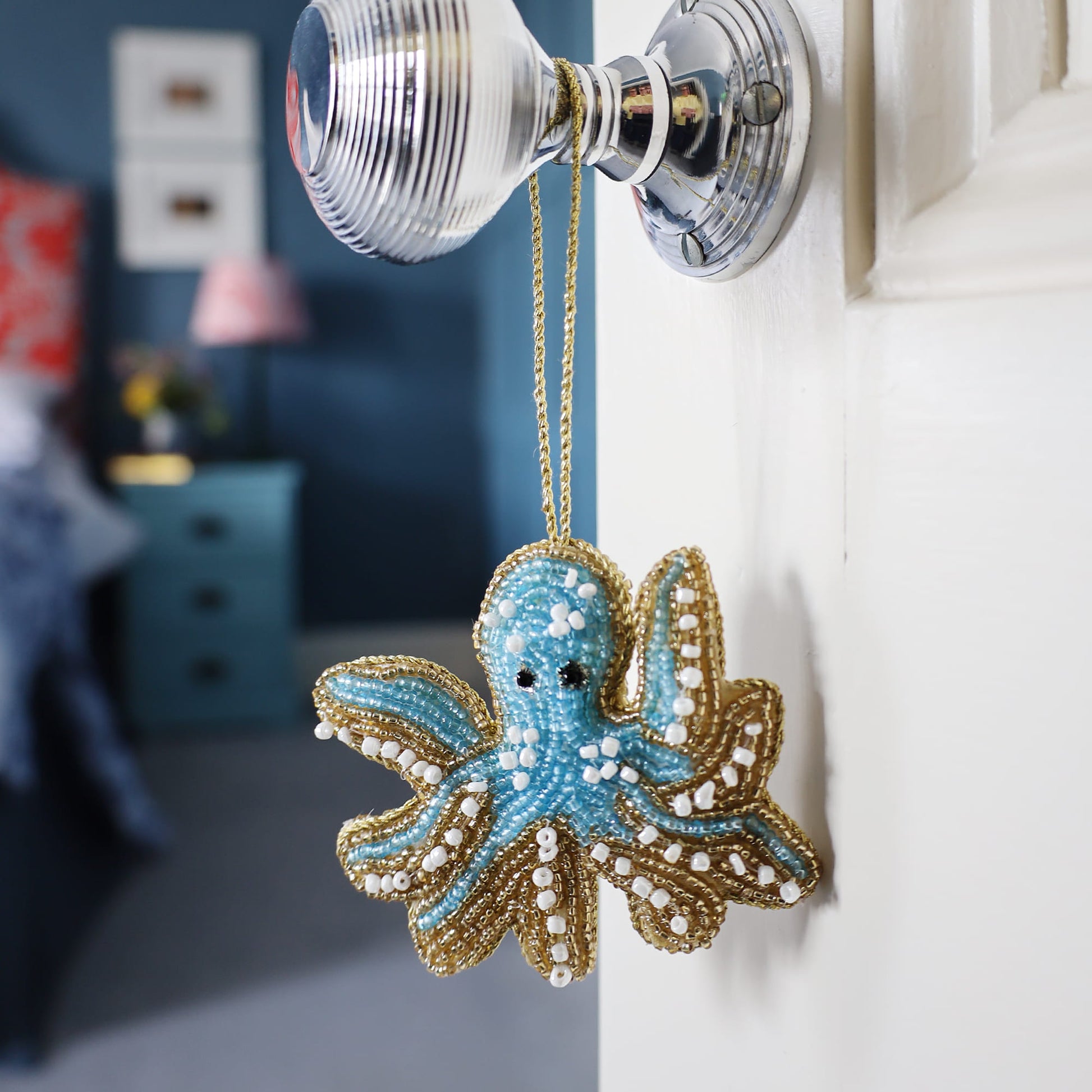 Decorative octopus ornament hanging on a door handle with a blurred room background