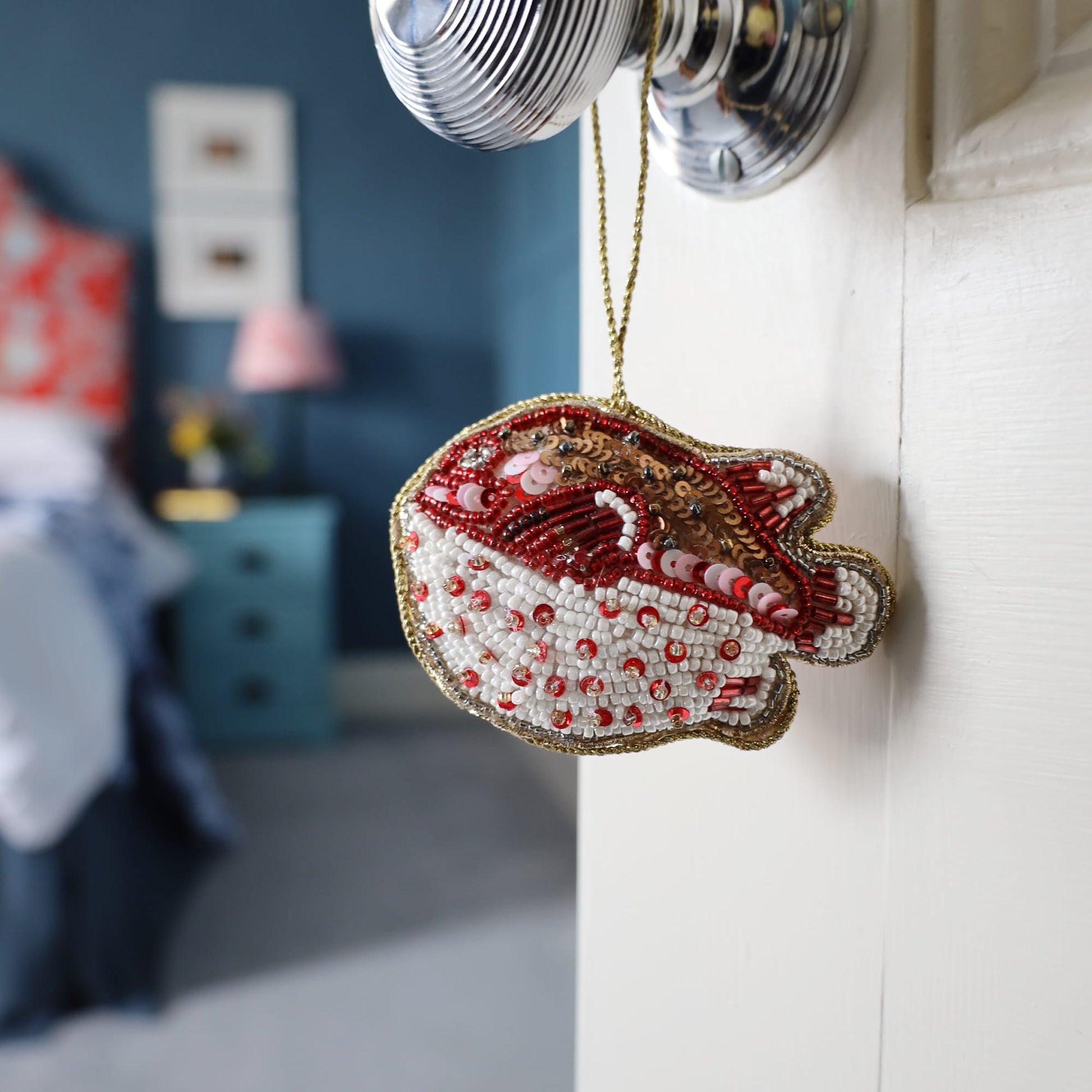 Decorative puffa fish ornament with red and white details hanging on a door handle.