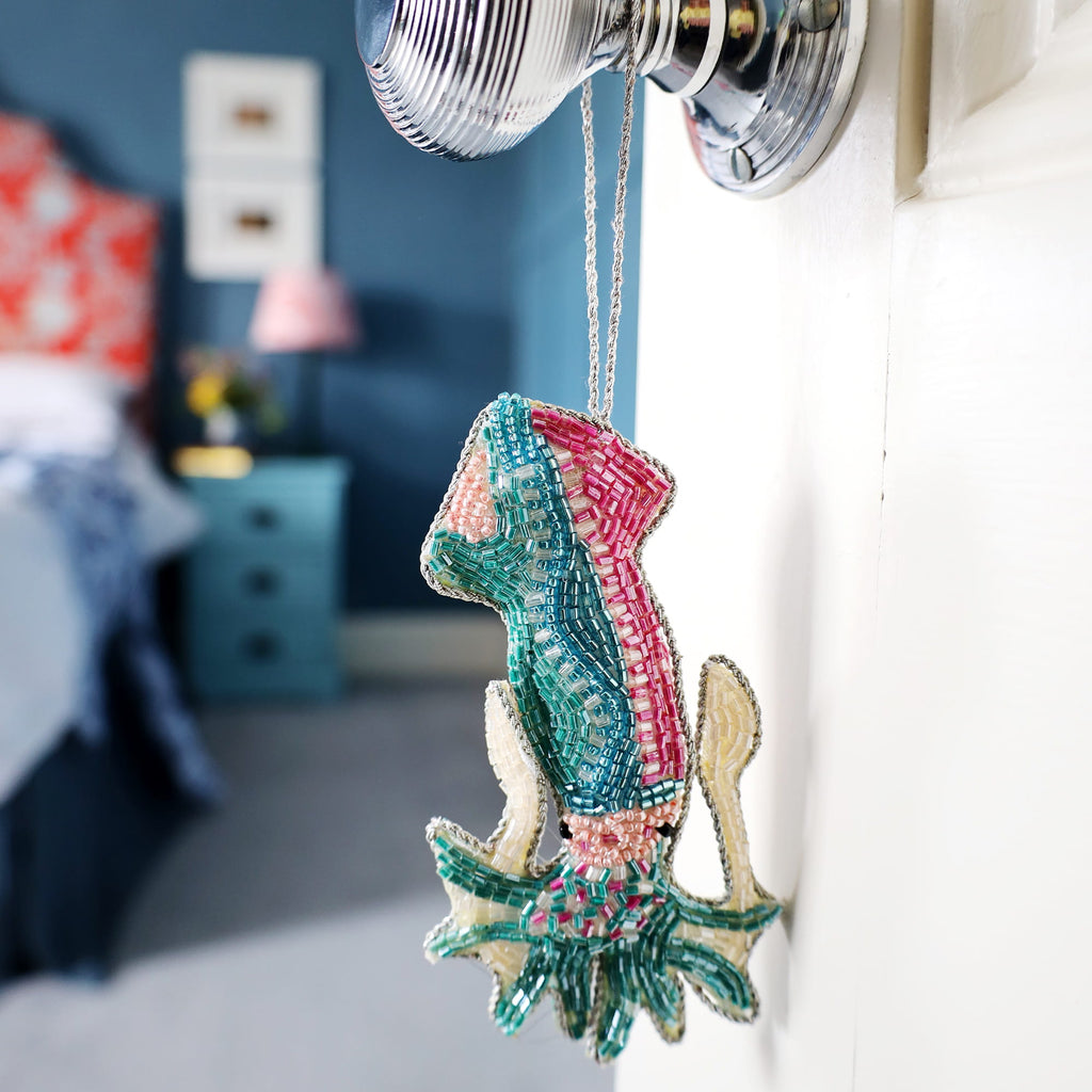 Decorative squid ornament hanging on a hook with a bedroom in the background