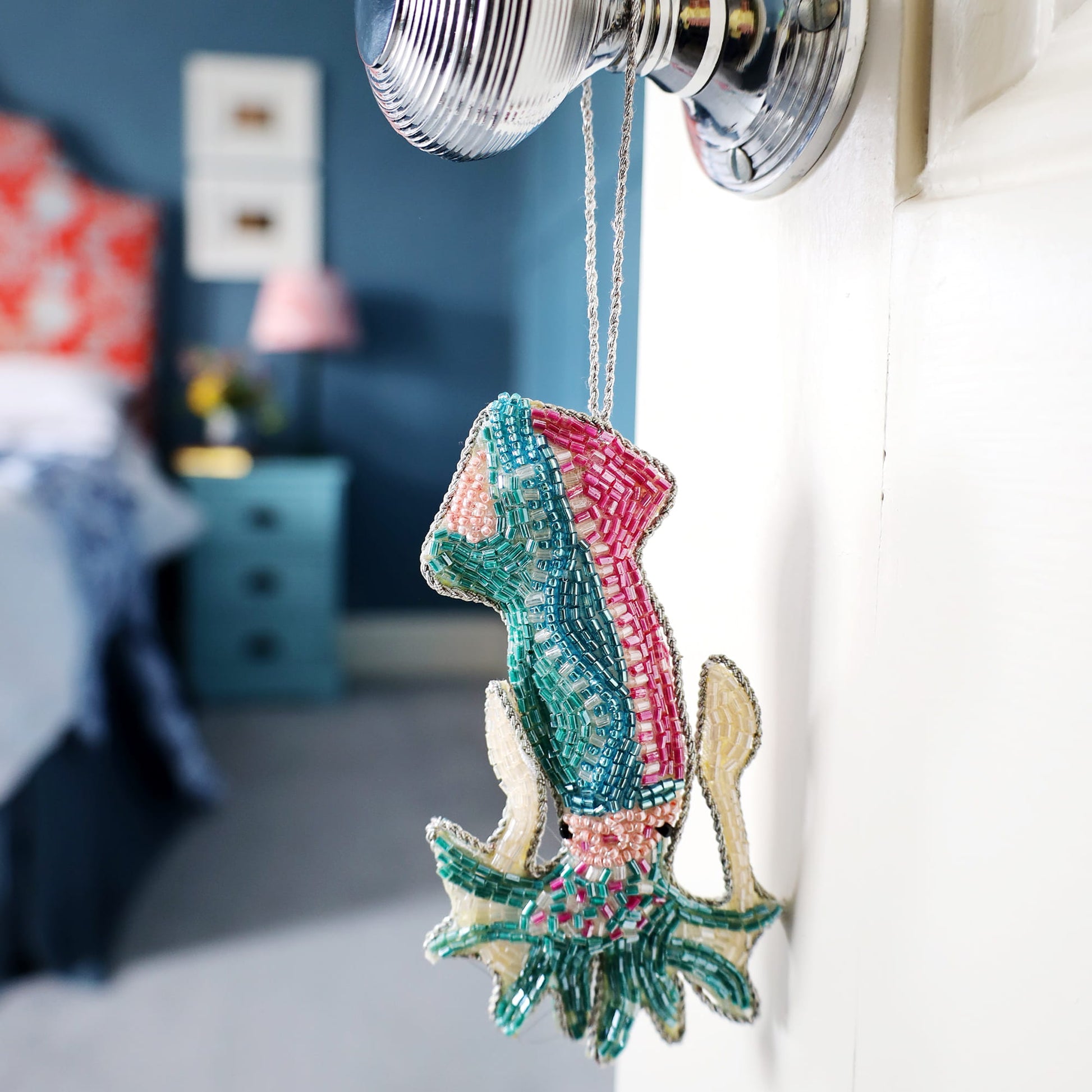 Decorative squid ornament hanging on a hook with a bedroom in the background