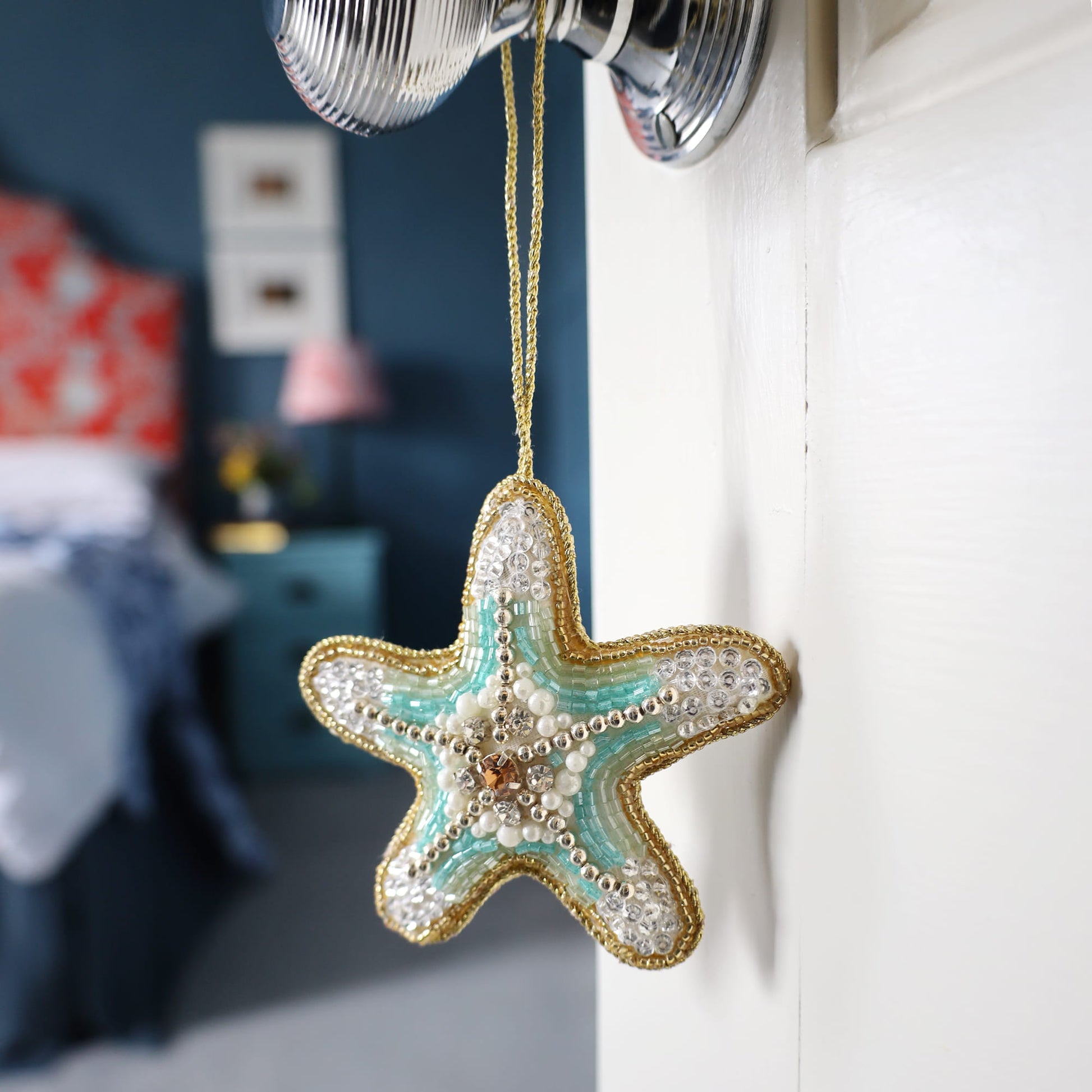 Decorative starfish ornament hanging on a hook with a blurred room background