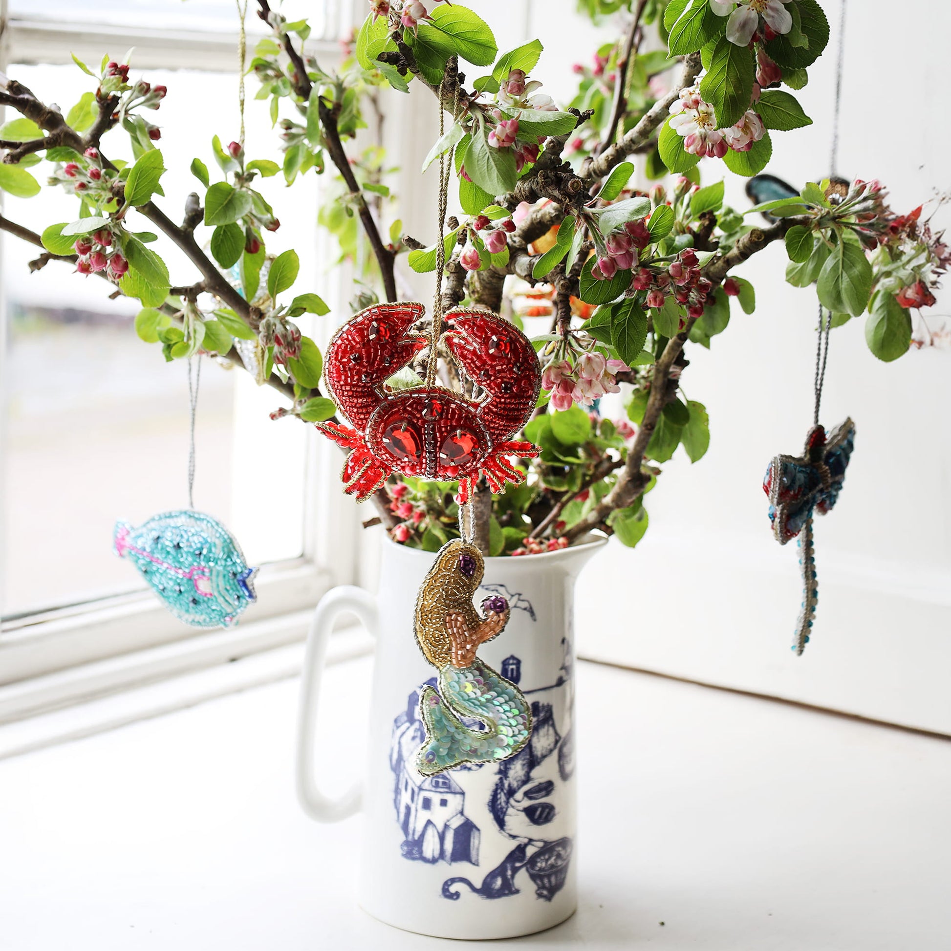 Decorative vase with floral branches and colorful animal ornaments on a light background