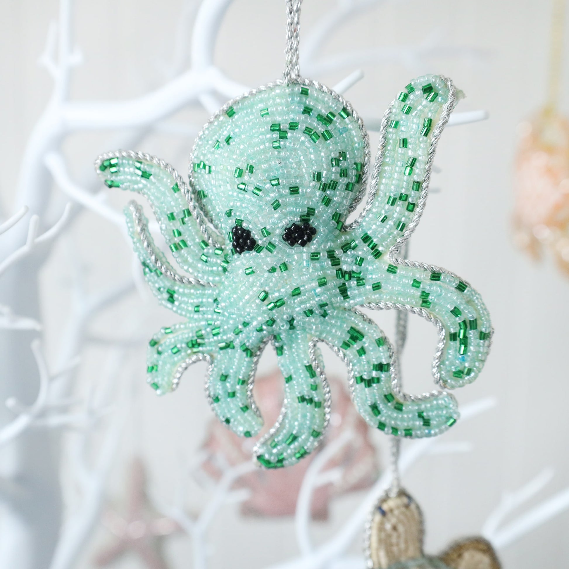 beaded aqua coloured christmas decoration in the shape of an octopus hanging from a tree