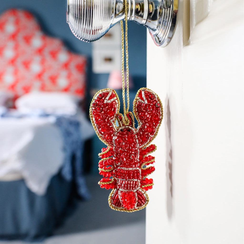 Red lobster ornament hanging on a light fixture with a blurred background