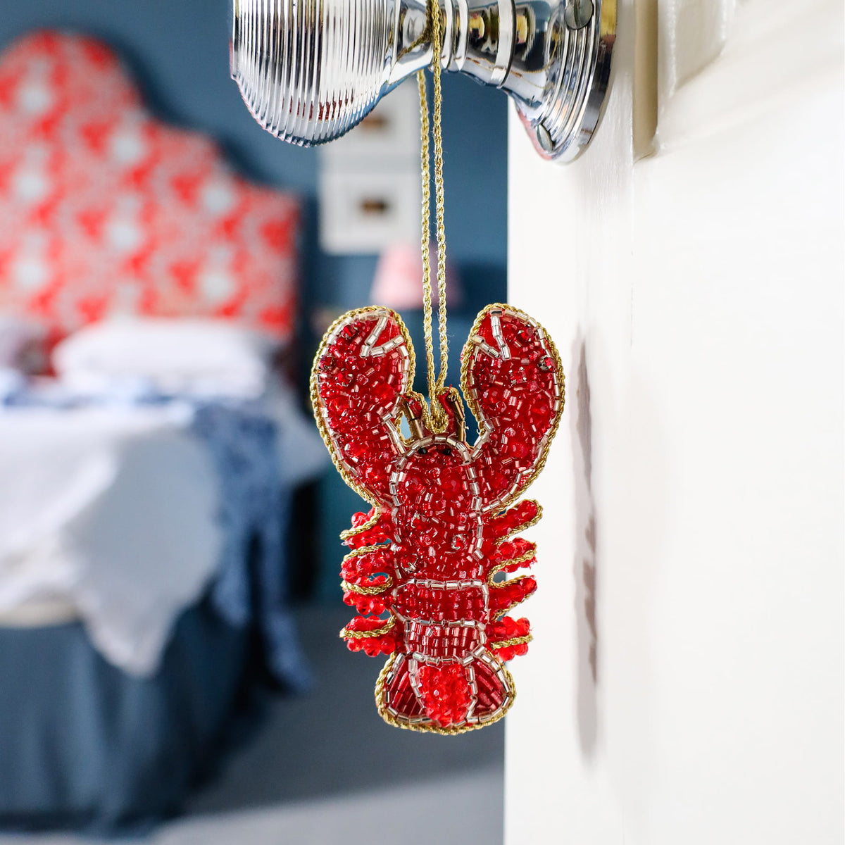 Red lobster ornament hanging on a light fixture with a blurred background