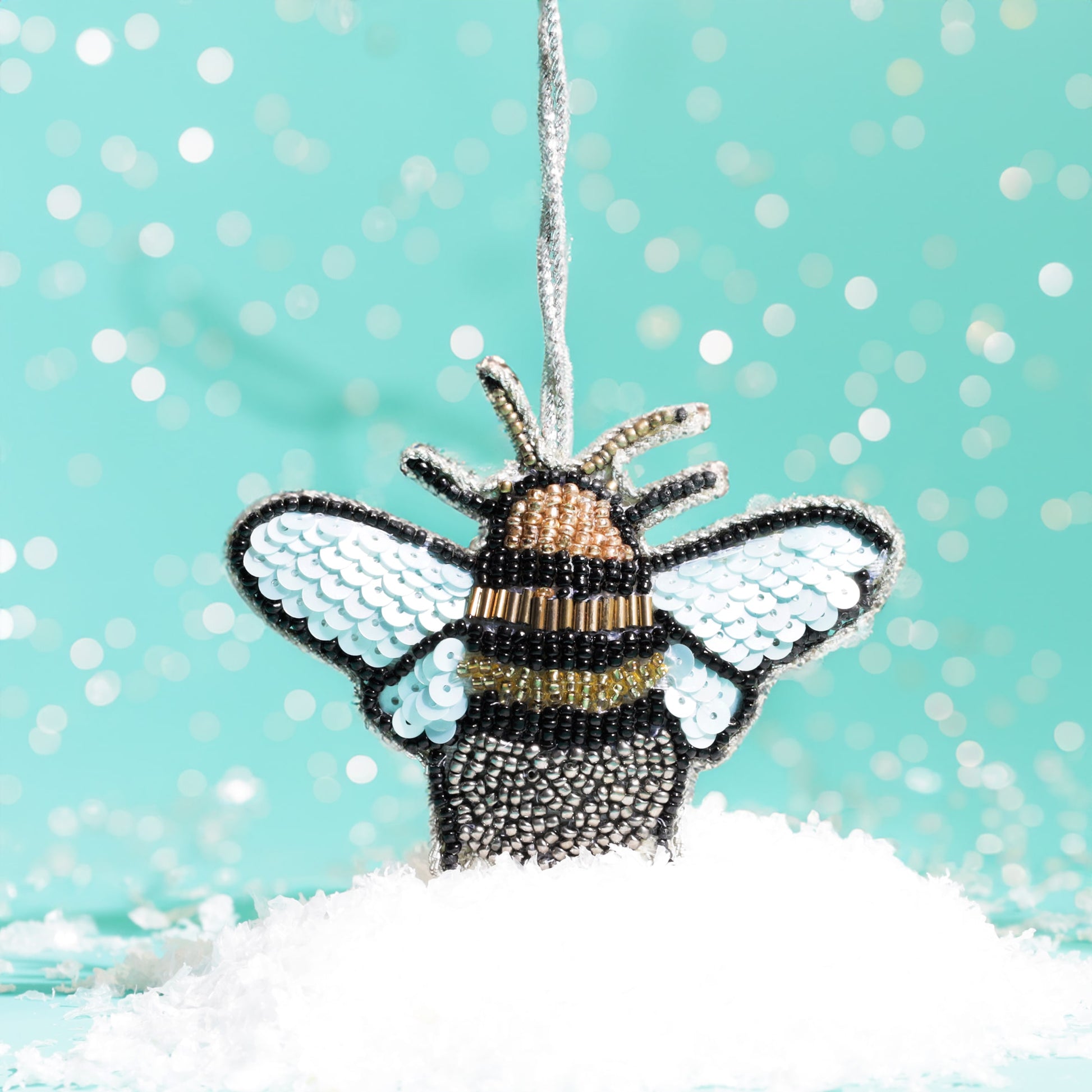 Bee-shaped ornament with sequins on a turquoise background