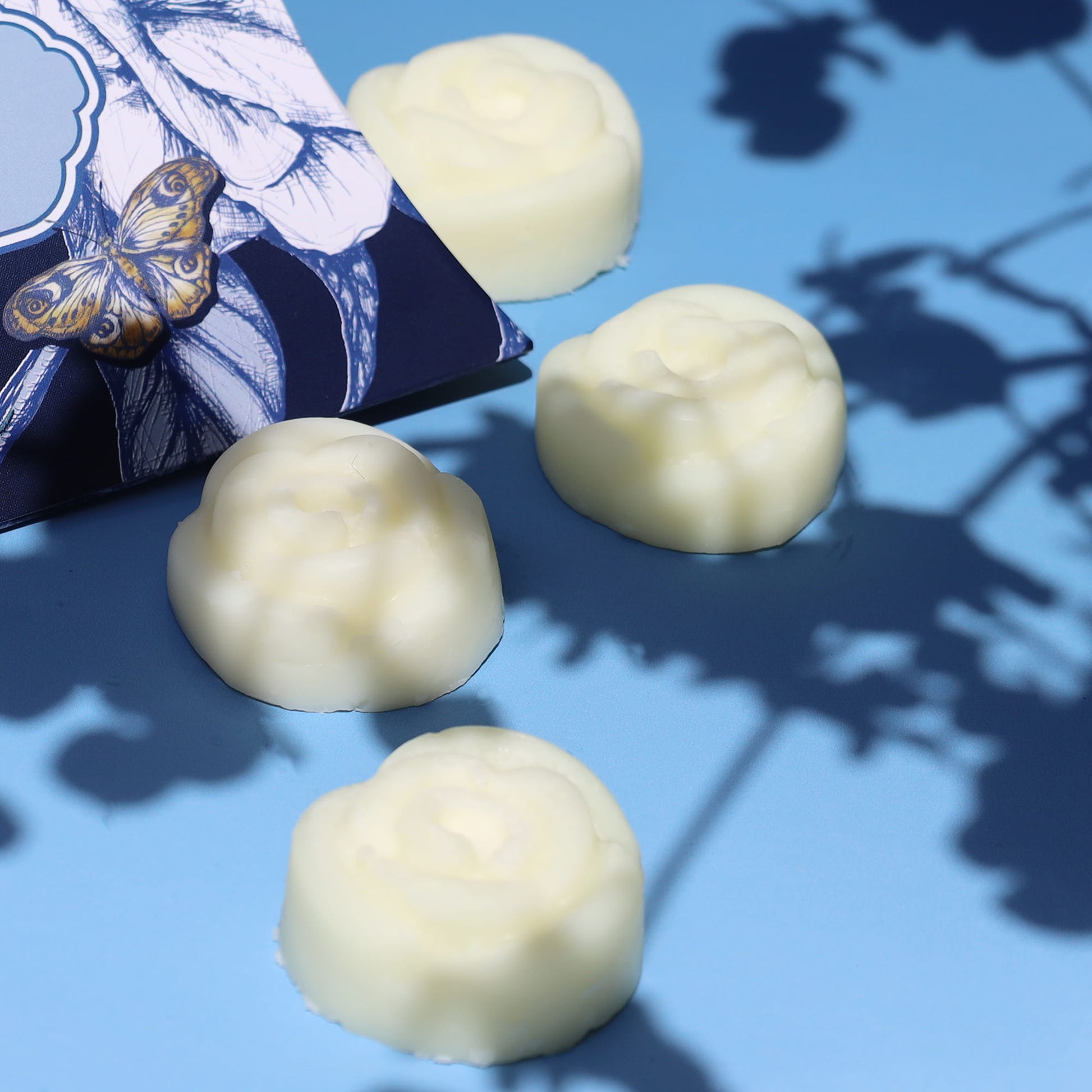 floral shaped wax melts on a blue surface with flower shadows in the background