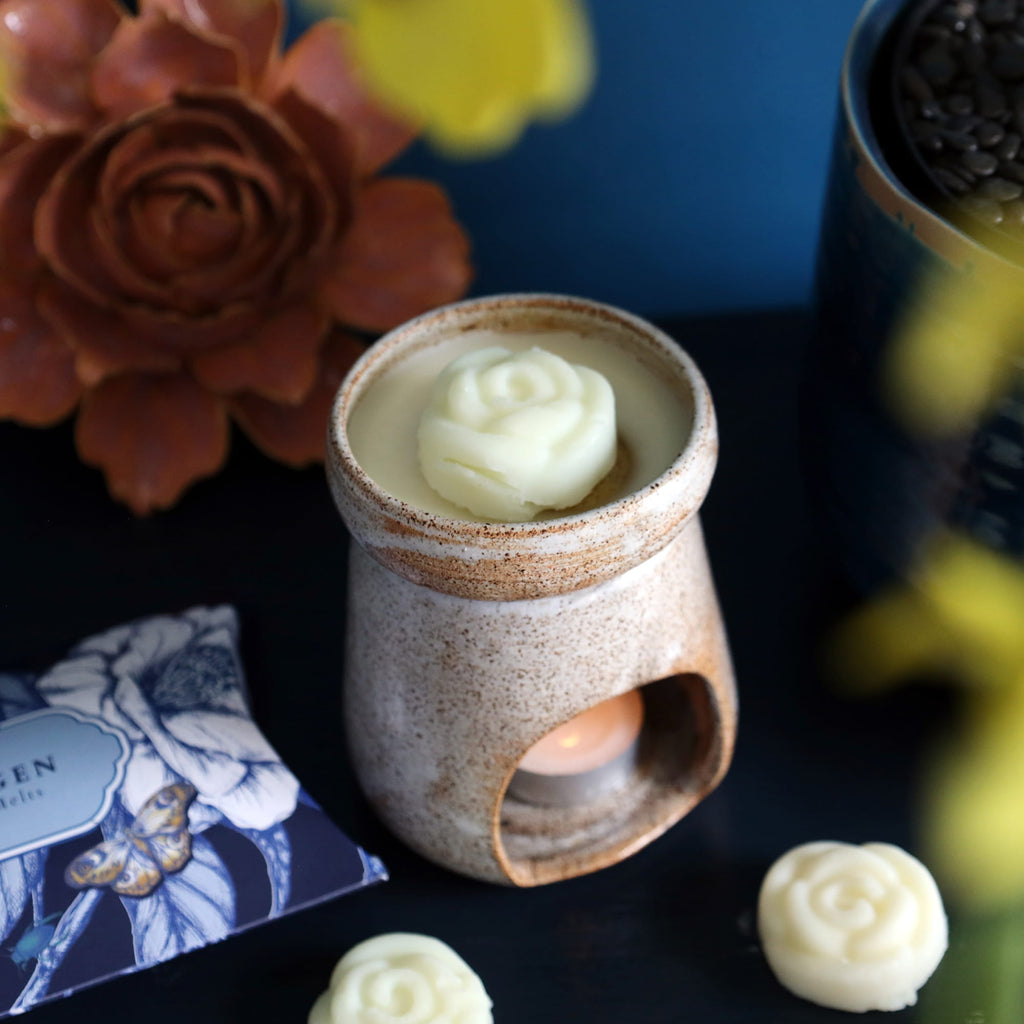 Ceramic wax warmer with floral wax melts on a dark surface with decorative elements.