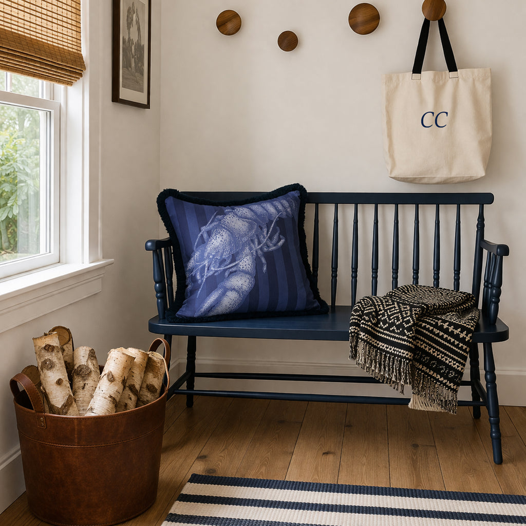 Navy wooden bench with decorative pillow, blanket, and log holder in a room with a window and wall hooks.