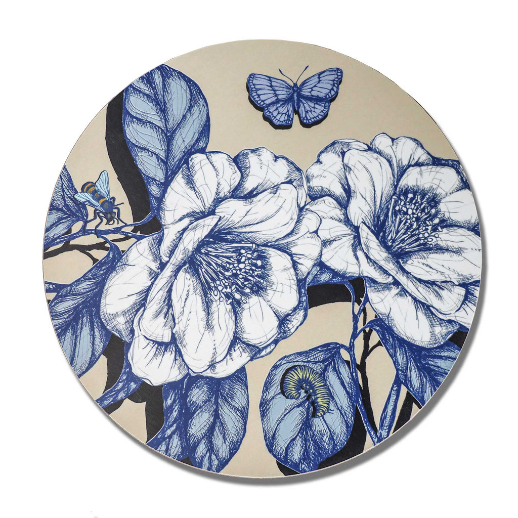 
Round decorative placemat featuring intricate blue botanical illustrations of two large blooming flowers, detailed leaves and delicate branches on a soft beige background. The nature-inspired design includes a blue butterfly, a blue and yellow bee, and a small green caterpillar resting on a leaf. Photographed from above against a plain white background.