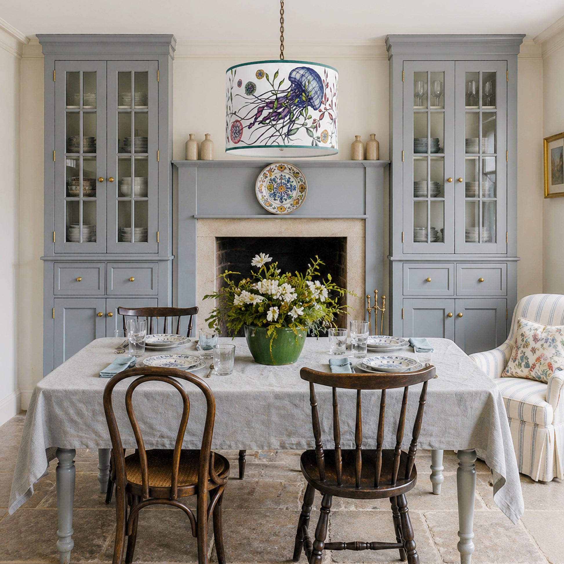 Dining room with grey cabinets, floral pendant light, and wooden chairs.