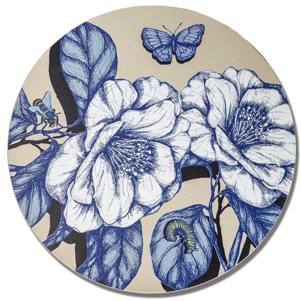 Cream Cornwall round placemat featuring intricate blue and white botanical illustrations of large blooming flowers, detailed leaves, a delicate blue butterfly, a small bee and a green caterpillar on a soft cream background, photographed against a clean white backdrop.