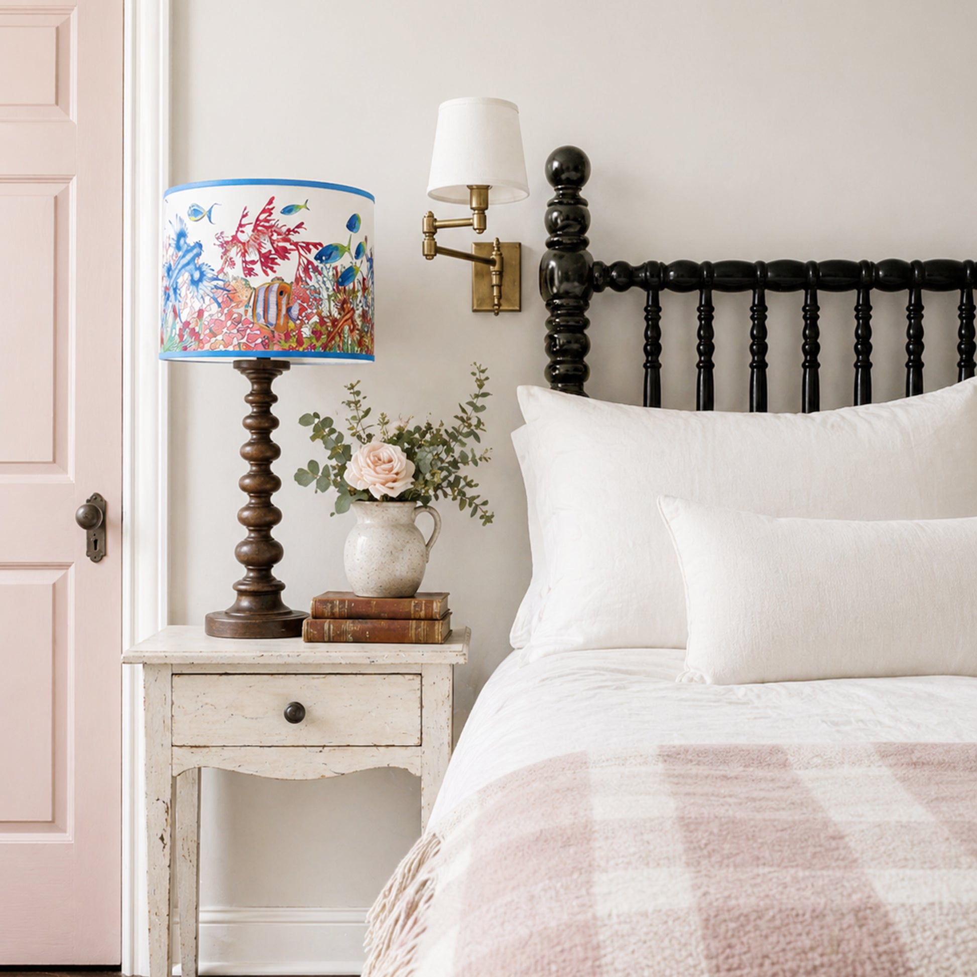 Bedroom with a lamp on a nightstand next to a bed with plaid blanket and white pillows.