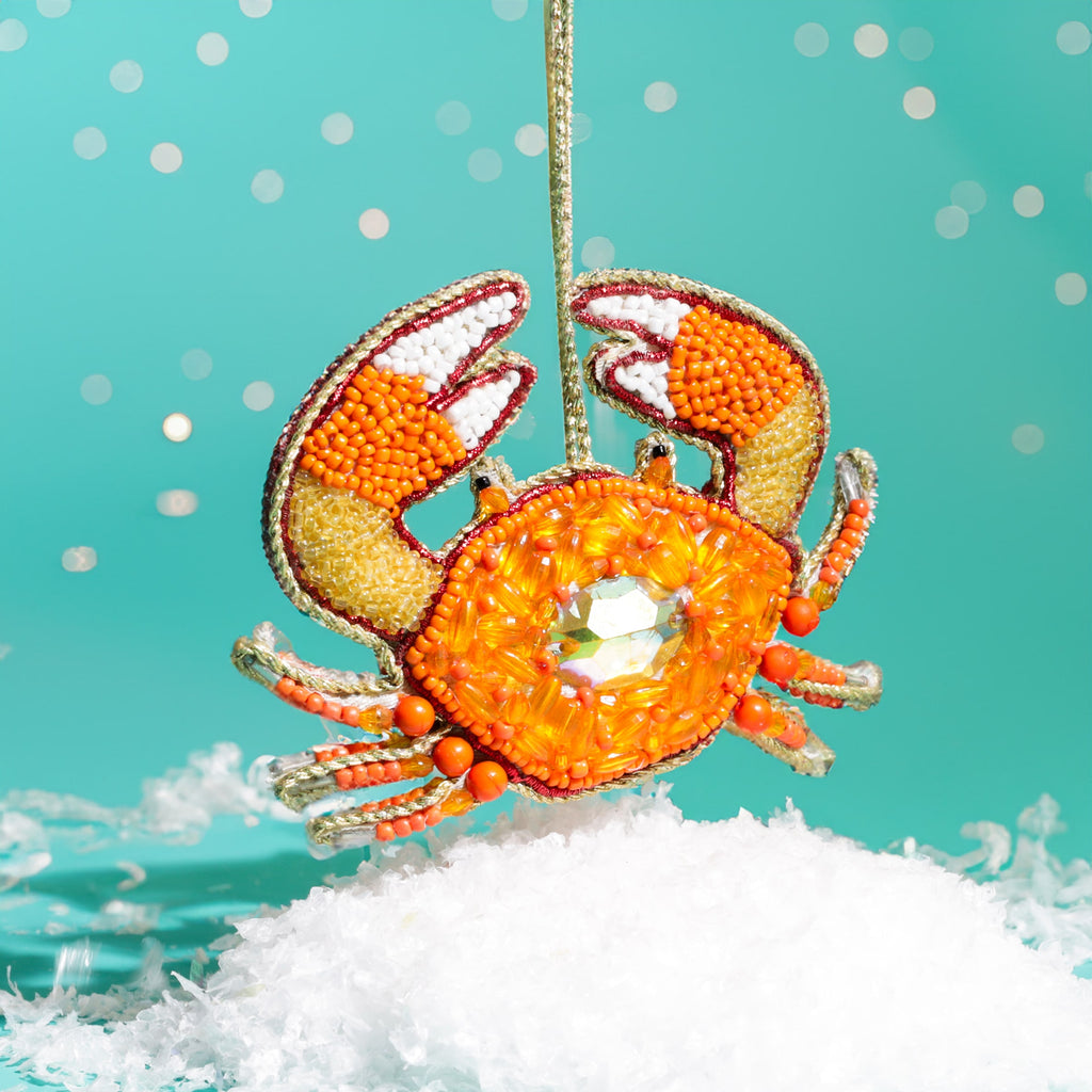 Decorative crab ornament with orange and white details on a turquoise background
