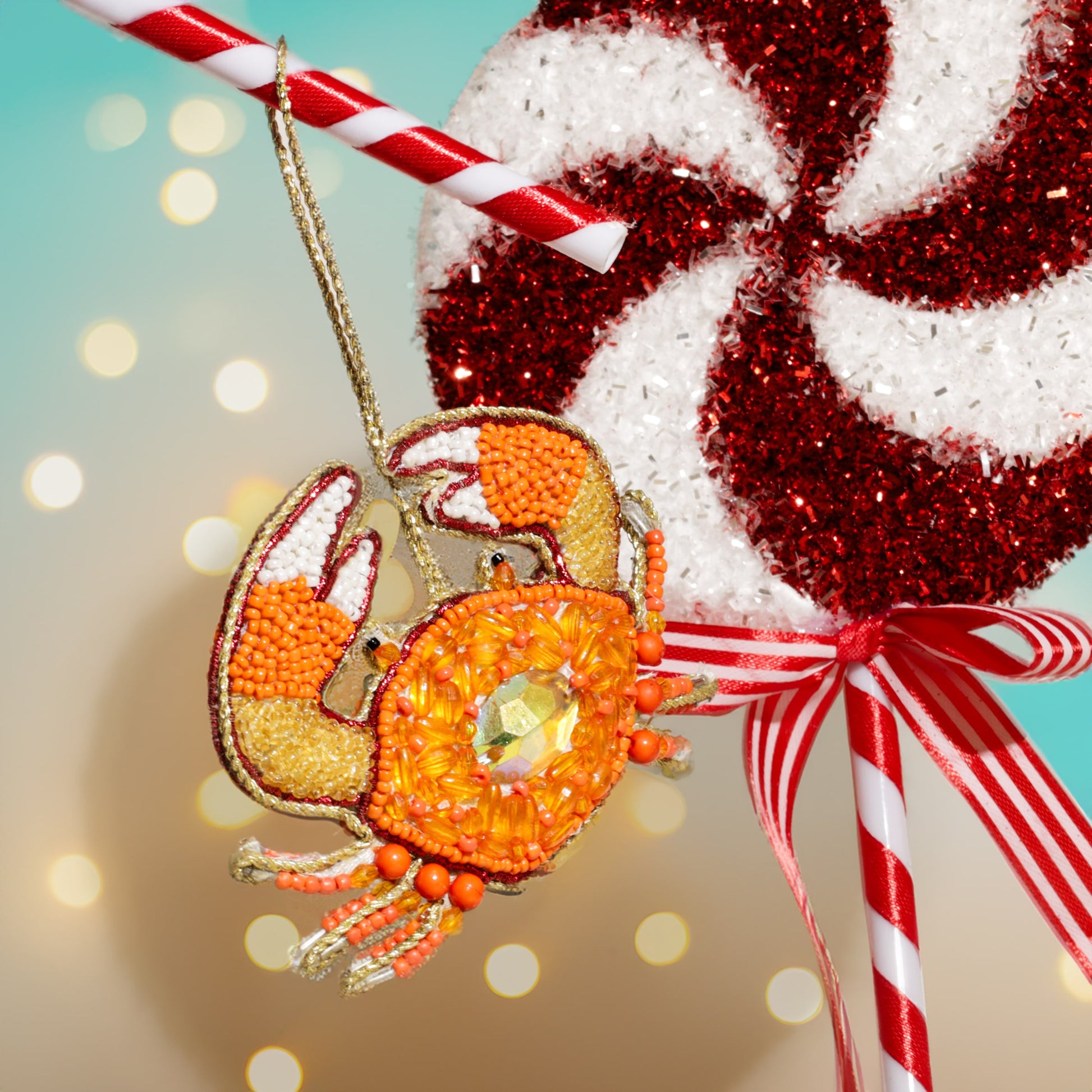 Decorative candy cane with a beaded crab ornament against a blurred light background