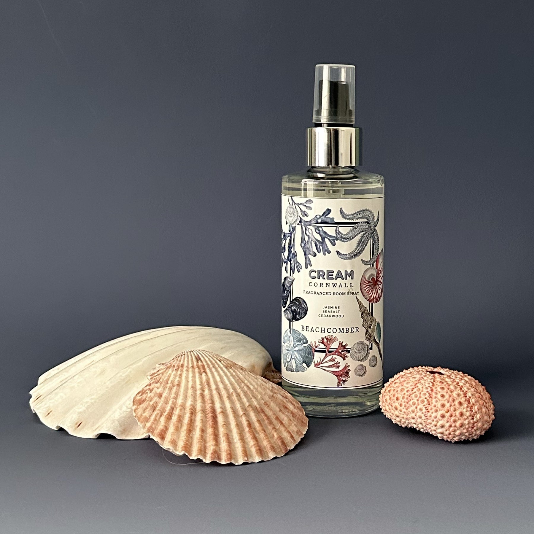 Fragrance Room Spray glass bottle with atomiser top,Beachcomber logo on label,next to three shells of various sizes